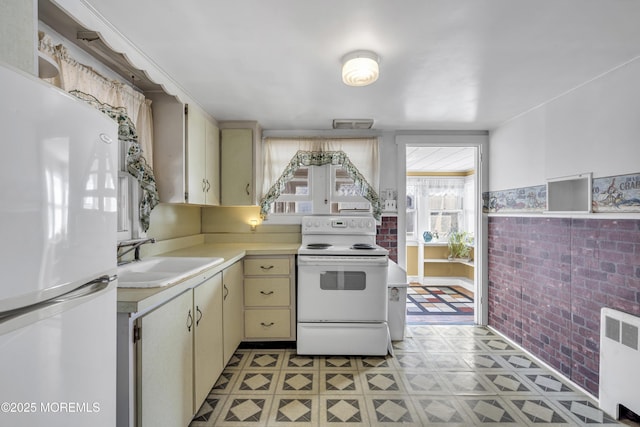 kitchen with radiator, sink, white appliances, and cream cabinets