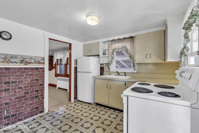 kitchen with radiator, cream cabinetry, sink, and white appliances