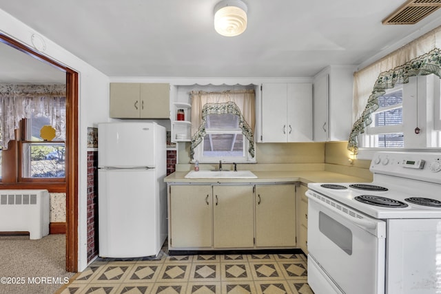 kitchen with sink, white appliances, radiator heating unit, and a wealth of natural light