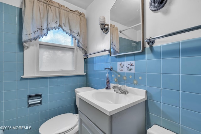 bathroom featuring toilet, tile walls, and vanity