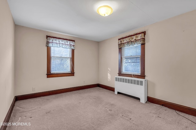 spare room featuring radiator and light colored carpet