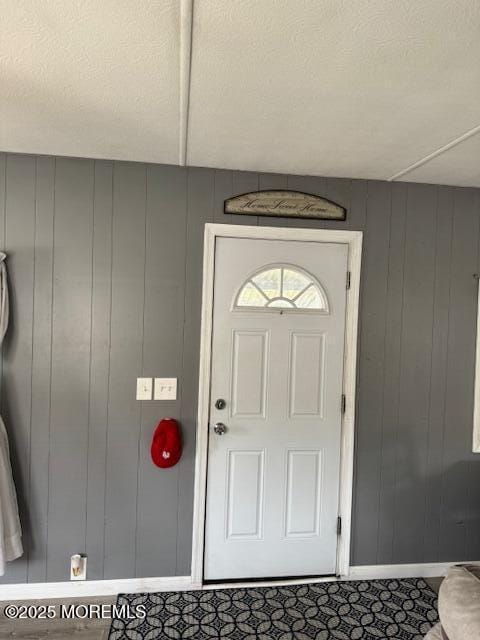 foyer with a textured ceiling and wooden walls