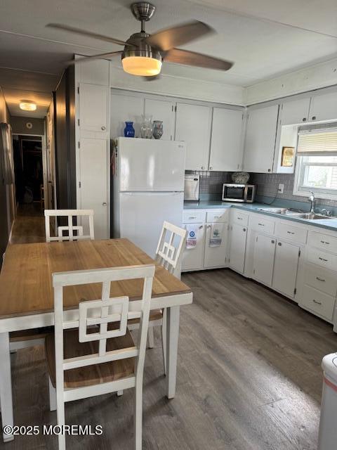 kitchen featuring backsplash, white cabinetry, white refrigerator, and sink