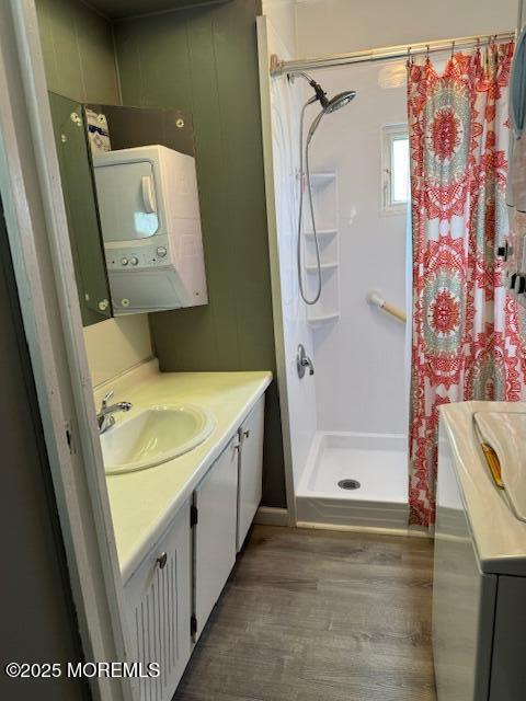 bathroom featuring curtained shower, stacked washer / dryer, vanity, and hardwood / wood-style floors