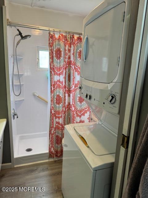 laundry room with dark hardwood / wood-style flooring and stacked washer and clothes dryer