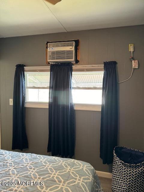 bedroom featuring multiple windows and a wall mounted air conditioner