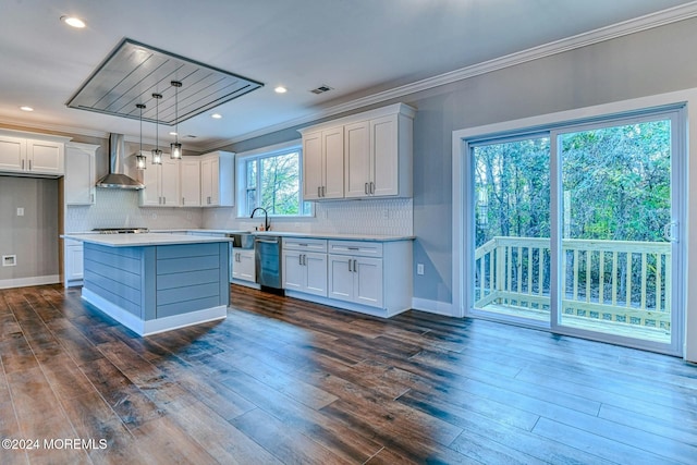 kitchen with decorative light fixtures, wall chimney range hood, appliances with stainless steel finishes, and white cabinetry