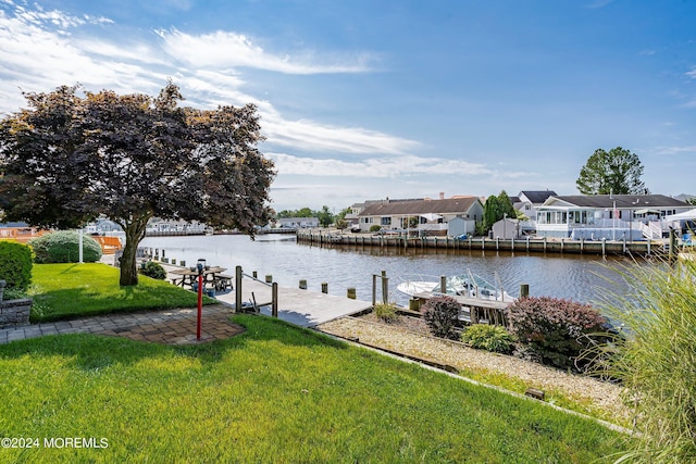 view of dock with a lawn and a water view