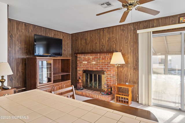 carpeted bedroom with a fireplace, ceiling fan, and wooden walls