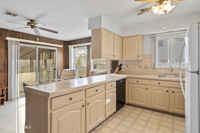 kitchen with sink, black dishwasher, white refrigerator, kitchen peninsula, and tile countertops