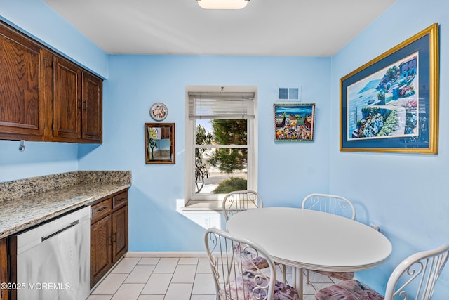 kitchen featuring light tile patterned floors, dishwasher, and light stone countertops