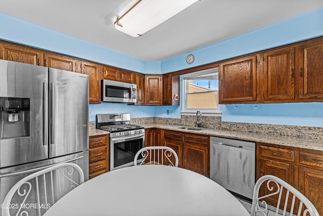 kitchen featuring light stone counters, sink, and stainless steel appliances