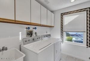 washroom with cabinets, sink, washer and clothes dryer, and light tile patterned floors