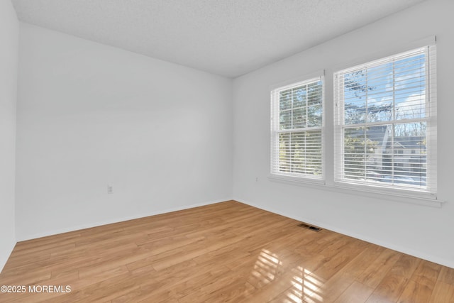 unfurnished room featuring a textured ceiling and light wood-type flooring