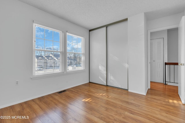 unfurnished bedroom featuring a textured ceiling, light wood-type flooring, and a closet