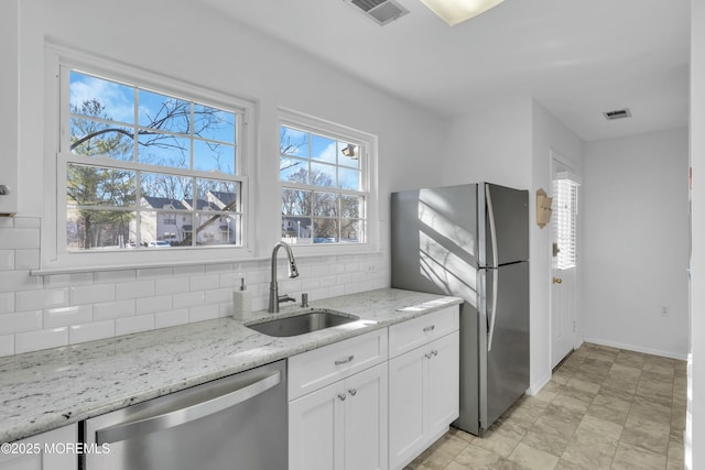 kitchen featuring white cabinets, stainless steel appliances, light stone countertops, sink, and tasteful backsplash