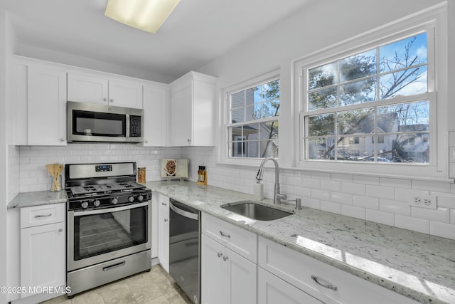 kitchen with appliances with stainless steel finishes, white cabinets, and sink