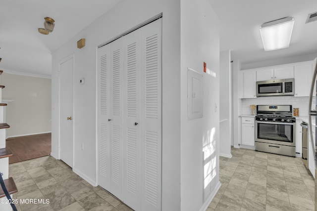 kitchen featuring appliances with stainless steel finishes, white cabinets, ornamental molding, and backsplash