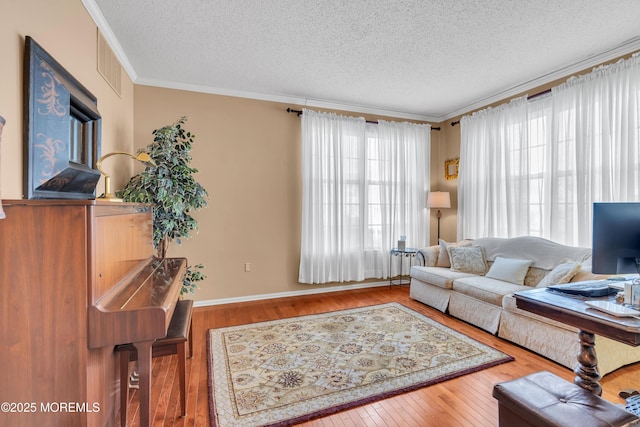 living room with hardwood / wood-style flooring, a textured ceiling, and ornamental molding