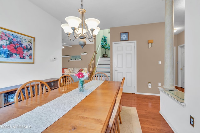 dining space featuring light hardwood / wood-style floors, ornate columns, and an inviting chandelier