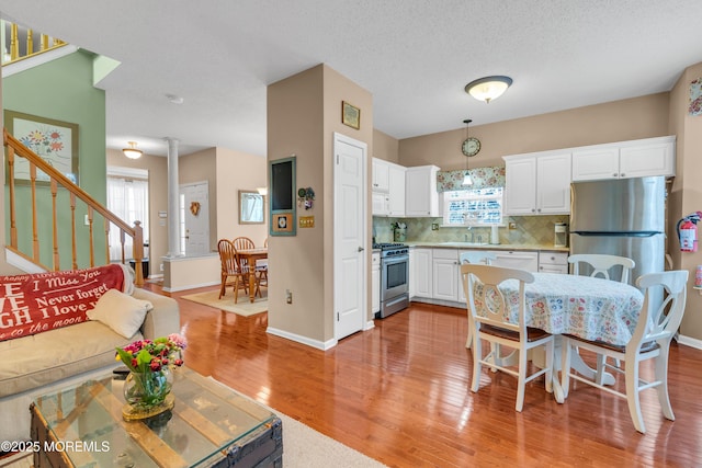 kitchen featuring hanging light fixtures, white cabinets, backsplash, and stainless steel appliances