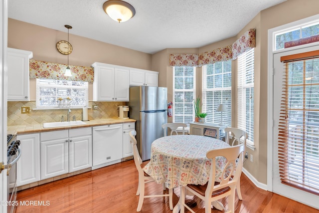 kitchen featuring sink, hanging light fixtures, appliances with stainless steel finishes, and white cabinets