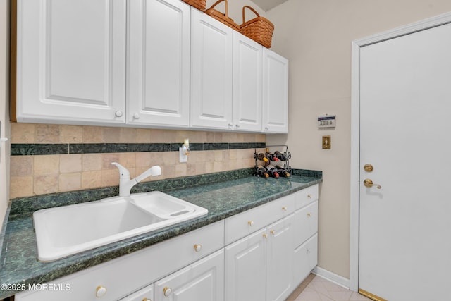 kitchen with light tile patterned floors, white cabinets, tasteful backsplash, and sink