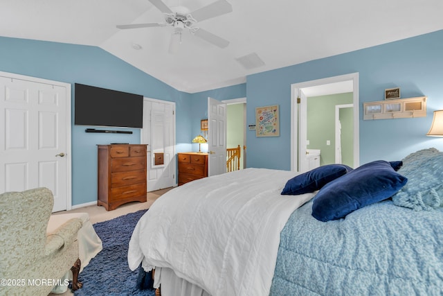 bedroom with ceiling fan, ensuite bathroom, light carpet, and lofted ceiling