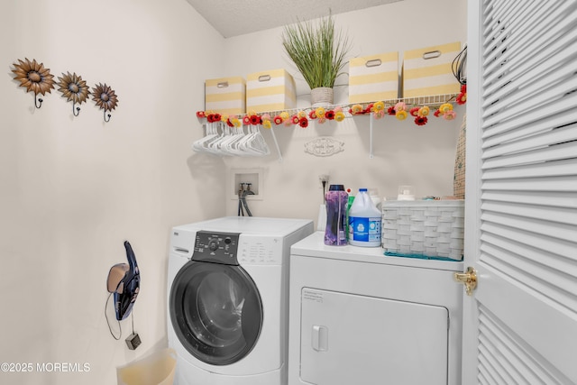 clothes washing area with washer and dryer and a textured ceiling