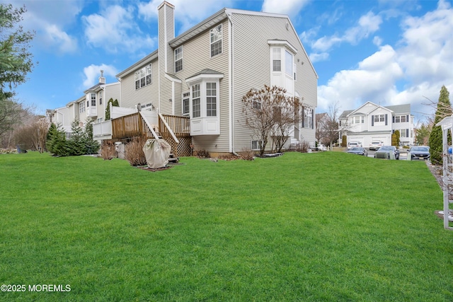 rear view of house featuring a lawn and a deck