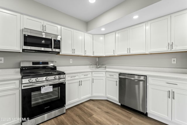 kitchen with white cabinets, wood-type flooring, appliances with stainless steel finishes, and sink