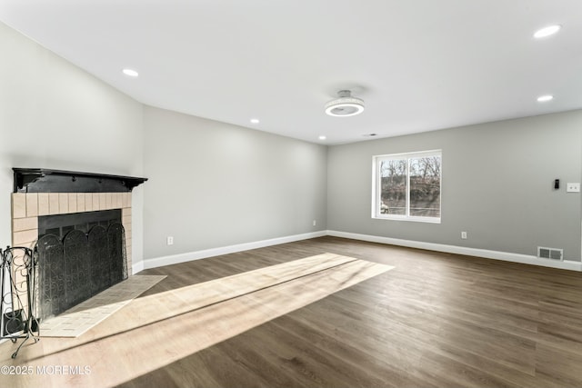 unfurnished living room featuring a brick fireplace and dark wood-type flooring