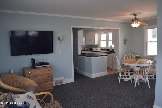 carpeted dining room with sink, ornamental molding, and ceiling fan