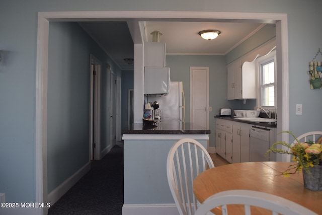 kitchen with white appliances, sink, ornamental molding, and white cabinetry