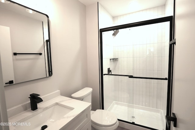 bathroom with toilet, vanity, and a shower with shower door