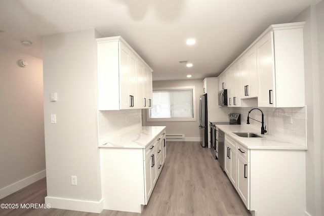 kitchen featuring white cabinets, stainless steel appliances, light stone countertops, sink, and tasteful backsplash