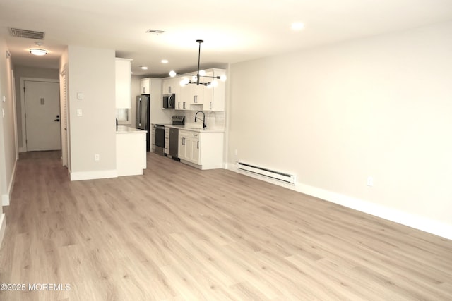 unfurnished living room featuring baseboard heating, light wood-type flooring, a chandelier, and sink