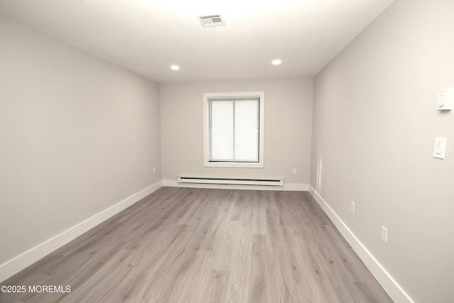 spare room with baseboard heating and light wood-type flooring