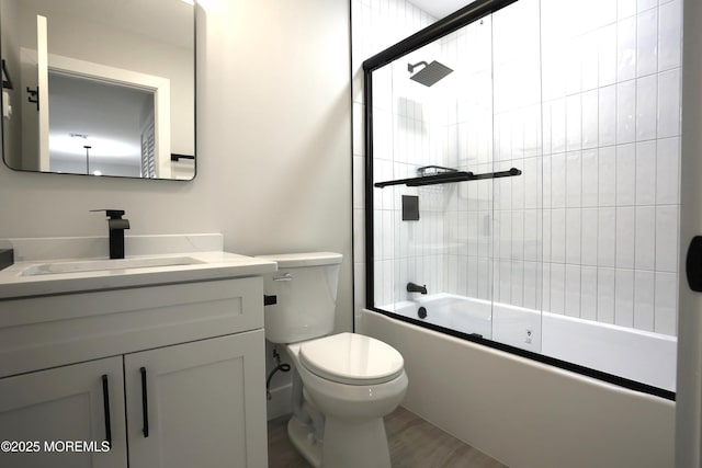 full bathroom featuring combined bath / shower with glass door, vanity, hardwood / wood-style flooring, and toilet