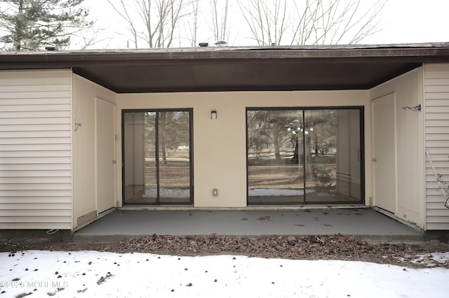 snow covered property entrance featuring a patio area