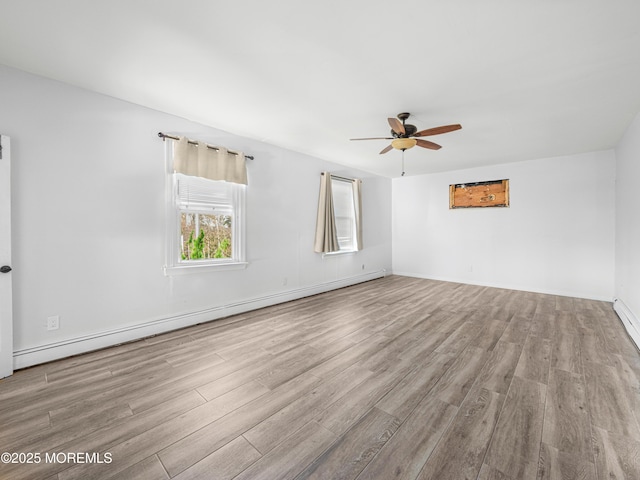 empty room with a baseboard heating unit, ceiling fan, and light hardwood / wood-style flooring