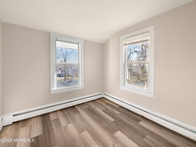 spare room featuring baseboard heating, vaulted ceiling, and light hardwood / wood-style flooring