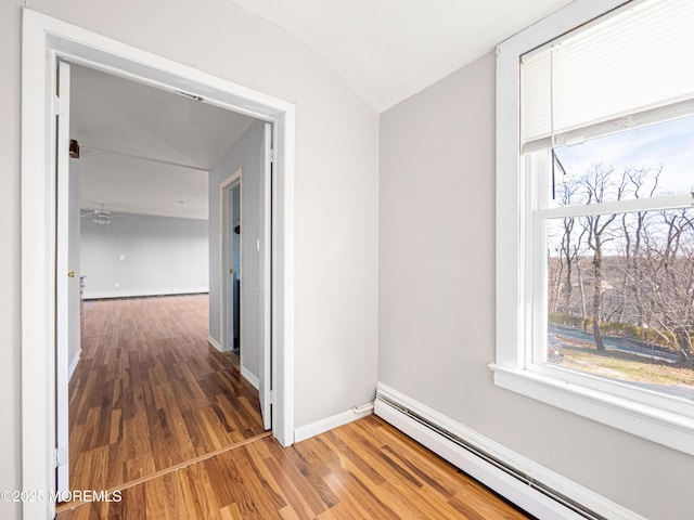 hall with hardwood / wood-style flooring, baseboard heating, and vaulted ceiling