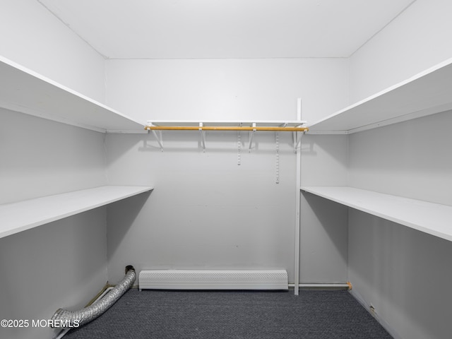 spacious closet with a baseboard heating unit and dark carpet