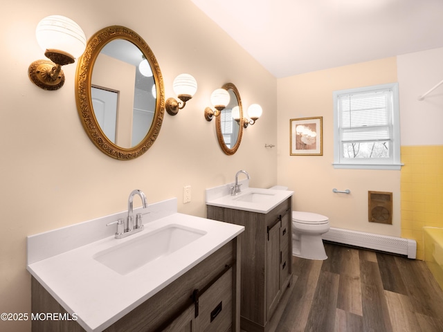 bathroom featuring hardwood / wood-style flooring, toilet, vanity, a bathing tub, and a baseboard radiator