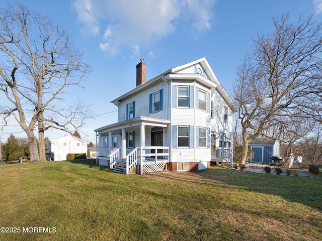 view of front of house featuring covered porch, a front lawn, and a storage shed