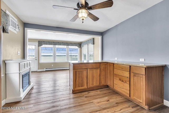 kitchen featuring ceiling fan, a baseboard heating unit, a wall mounted AC, and light wood-type flooring