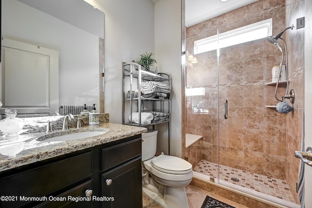 bathroom with walk in shower, vanity, tile patterned floors, and toilet