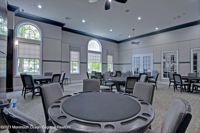 dining room with ceiling fan, light colored carpet, and crown molding