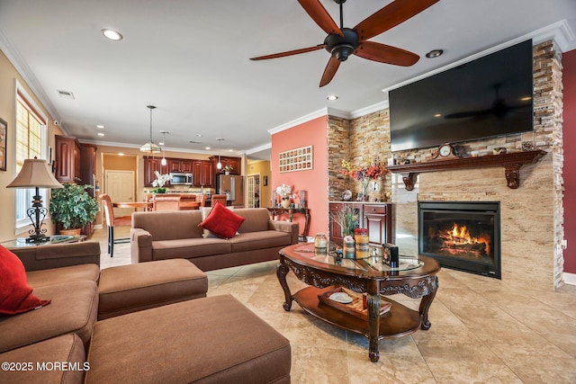 living room featuring ceiling fan, light tile patterned floors, a fireplace, and crown molding